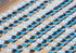 Pattern of blue and white umbrellas and lounge chairs on a sandy beach.