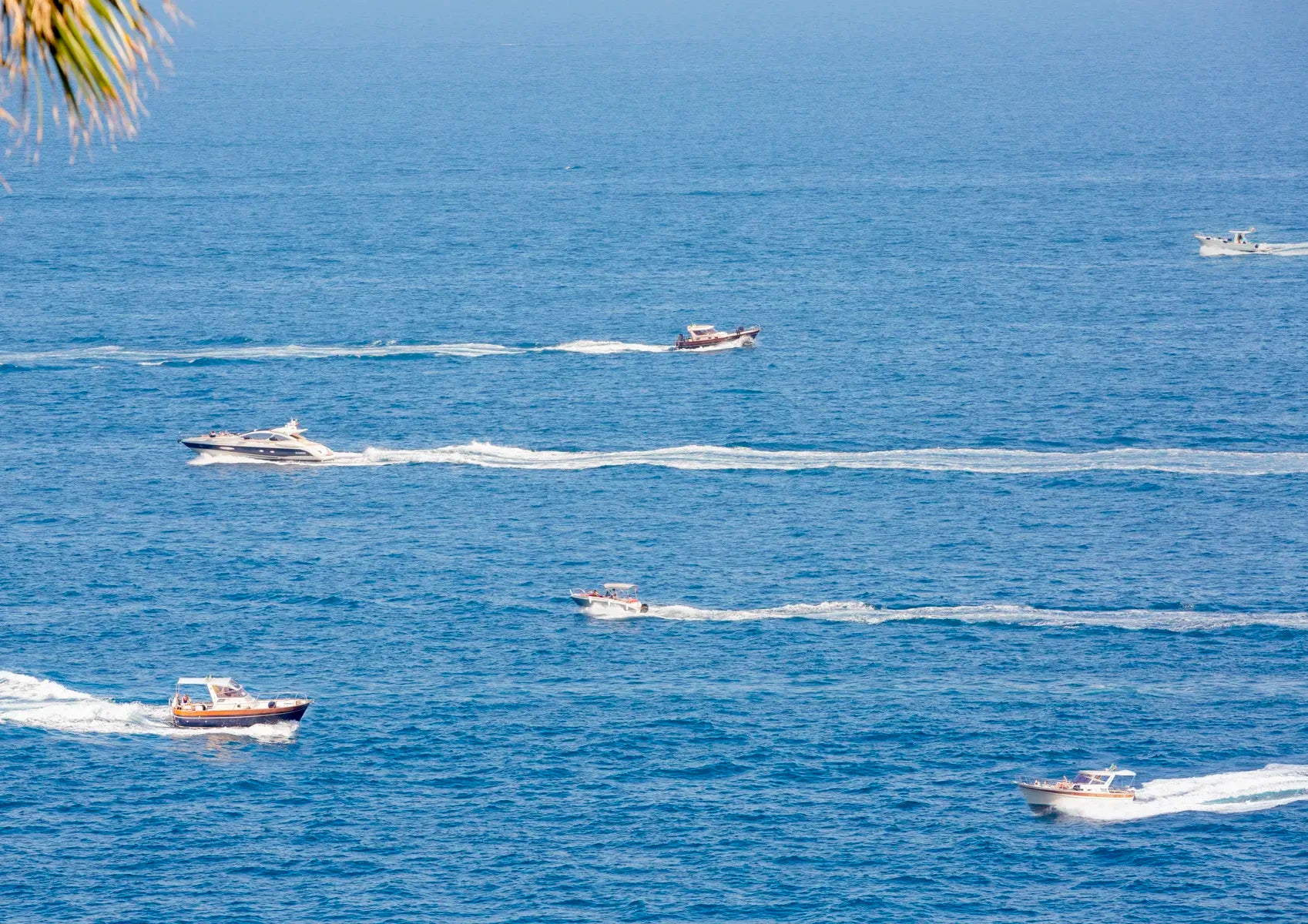 Multiple boats on a body of water with a clear sky