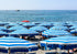 Beach scene with blue and white striped umbrellas and chairs on a sandy beach.