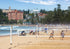 Beach volleyball game on a sandy court with buildings and trees in the background