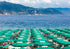 Umbrellas and people on a beach with mountains and ocean in the background