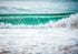 Wave crashing onto a beach with a clear sky