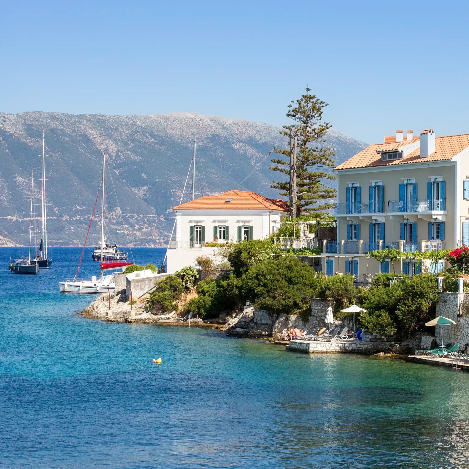 Coastal scene with houses, boats, and mountains in the background