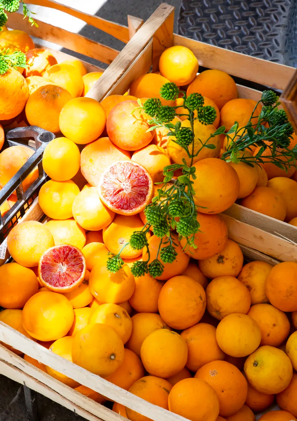 Wooden crate filled with  blood oranges sitting on a dark bench