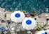 Outdoor cafe with white tables and blue and white umbrellas by the sea.