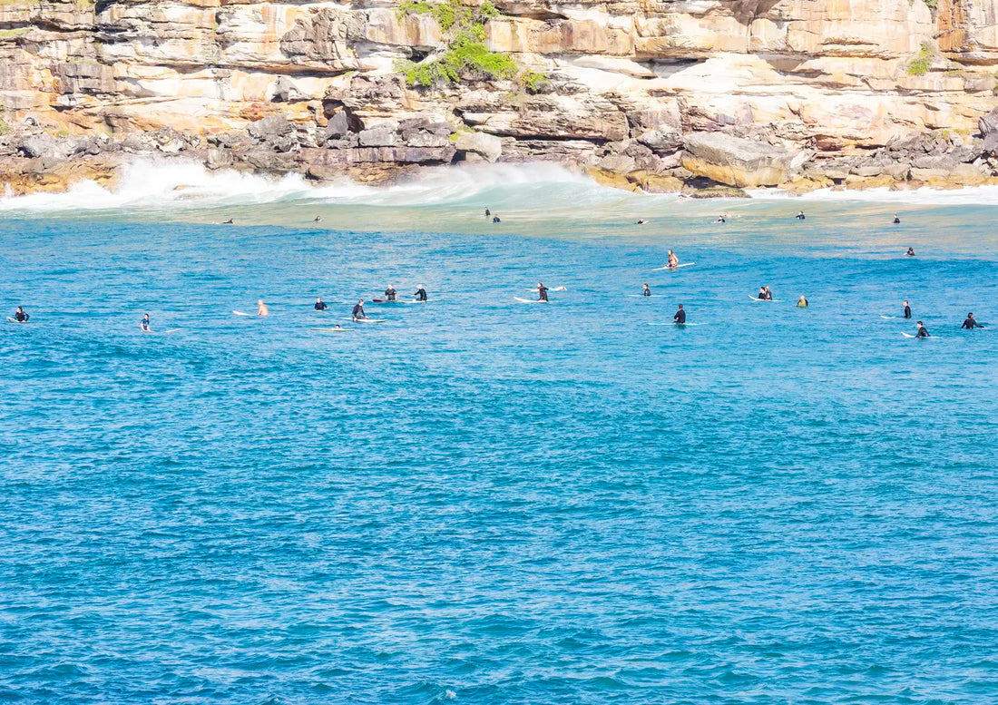 Surfers in the water with a rocky cliff in the background