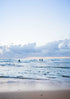 People surfing on a beach with a cloudy sky