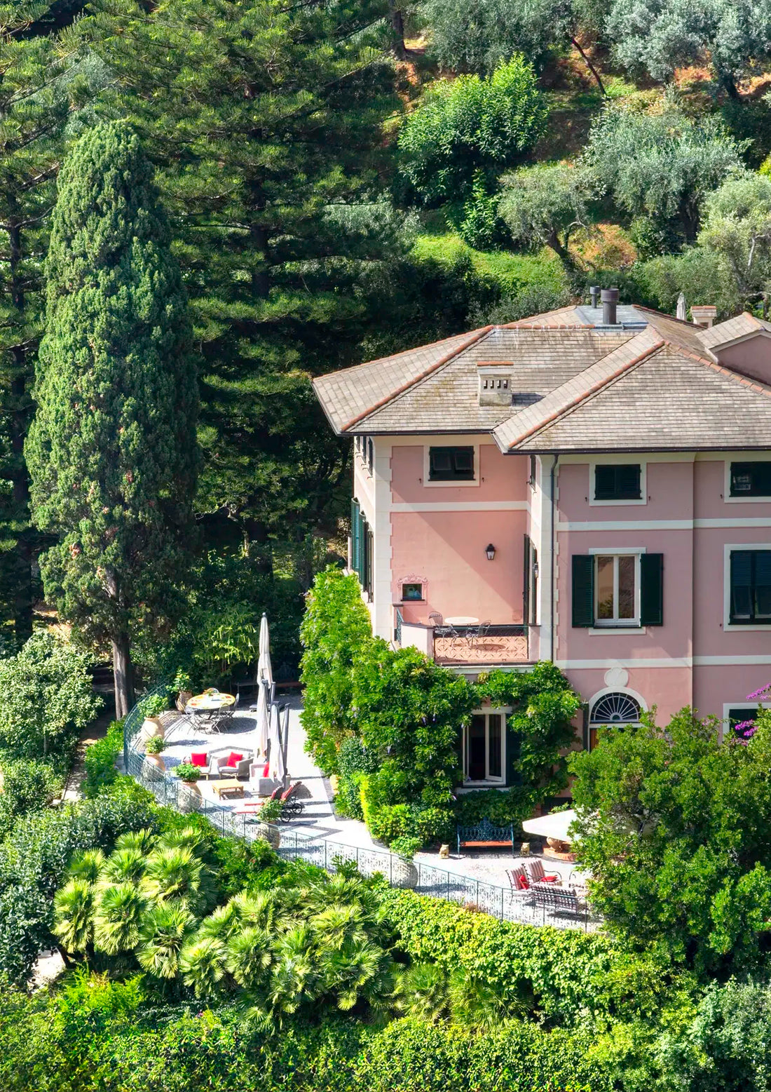Large pink house surrounded by green trees and gardens