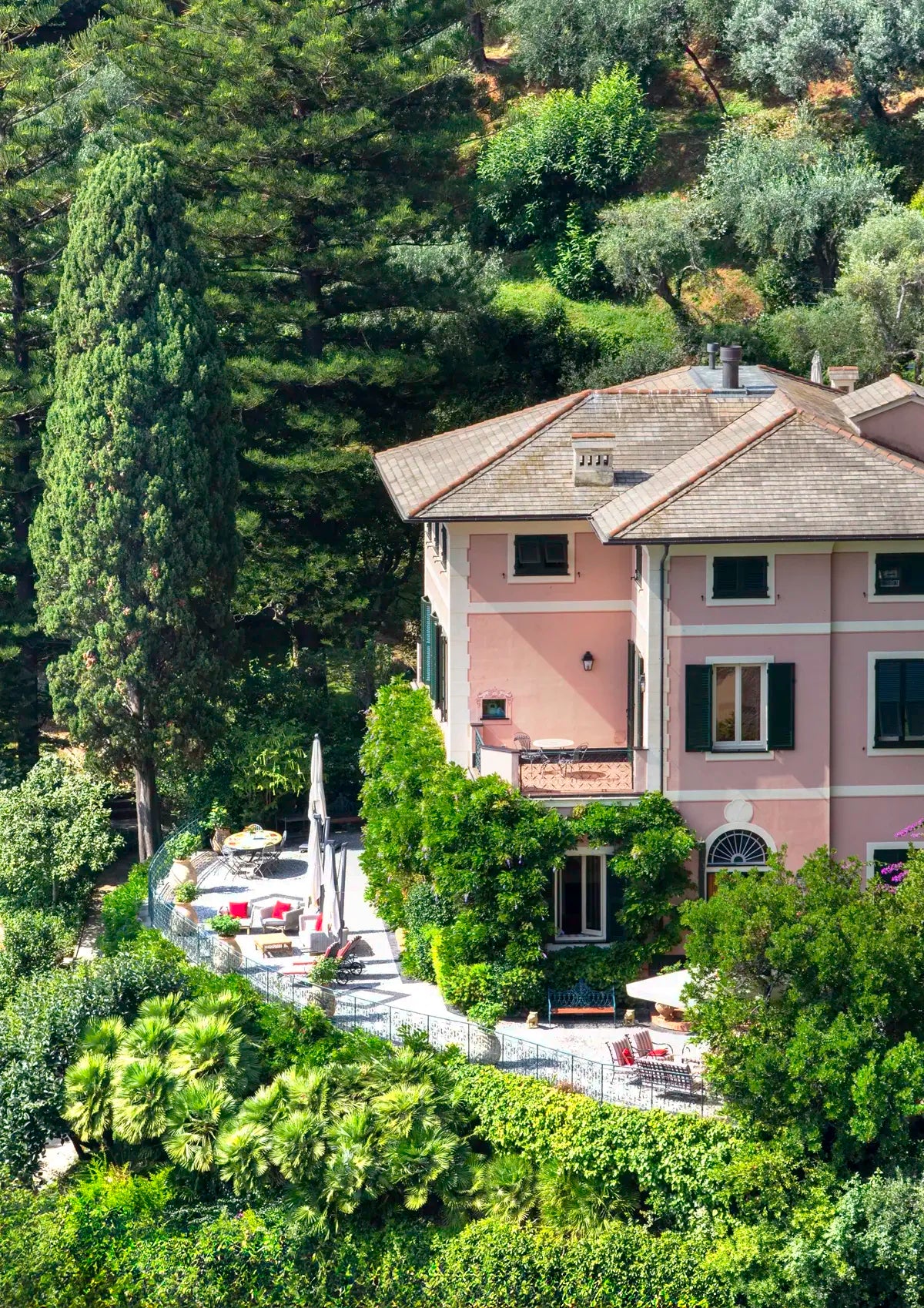 Large pink house surrounded by green trees and gardens