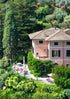 Large pink house surrounded by green trees and gardens