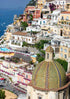 Hilly coastal Portofino town with colorful buildings and a prominent dome.